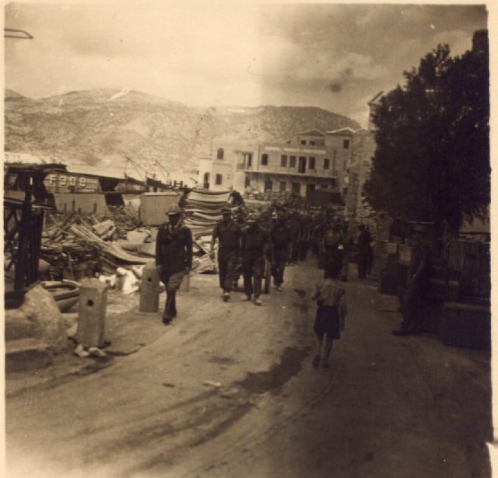 Οι Γερμανοί αποβιβάζονται στην Κάρπαθο. Προηγείται ο λοχαγός Bethege, χωρίς να τον υπολογίζει ο πιτσιρίκος που περνάει  δίπλα του 