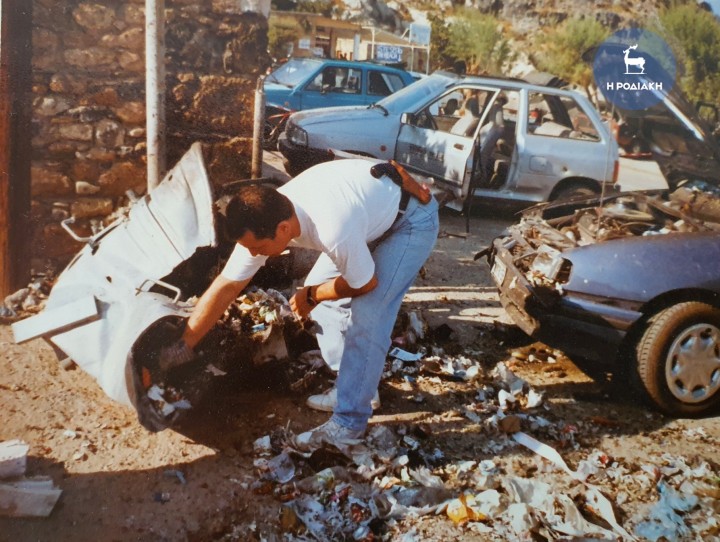 Από το χτύπημα στη Λίνδο. Αστυνομικός της Υ.Α Ρόδου, συγκεντρώνει κομμάτια και θραύσματα μέσα από σιδερένιο κάδο. Λίγα λεπτά νωρίτερα οι τρομοκράτες τον είχαν ανατινάξει, προκαλώντας χάος, αλλά ευτυχώς όχι θύματα
